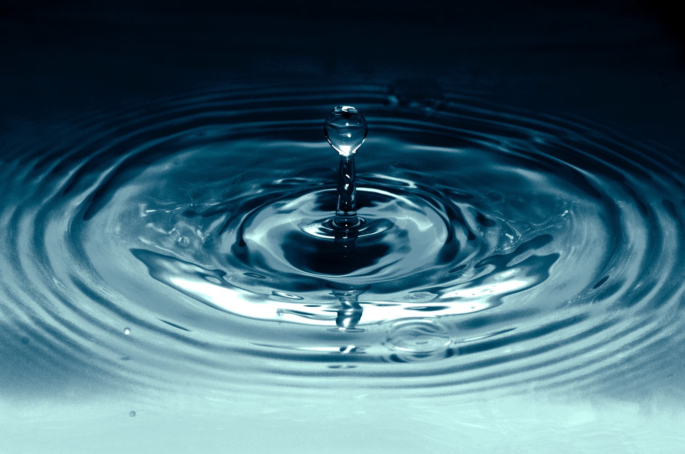 A drop of water rippling a still surface